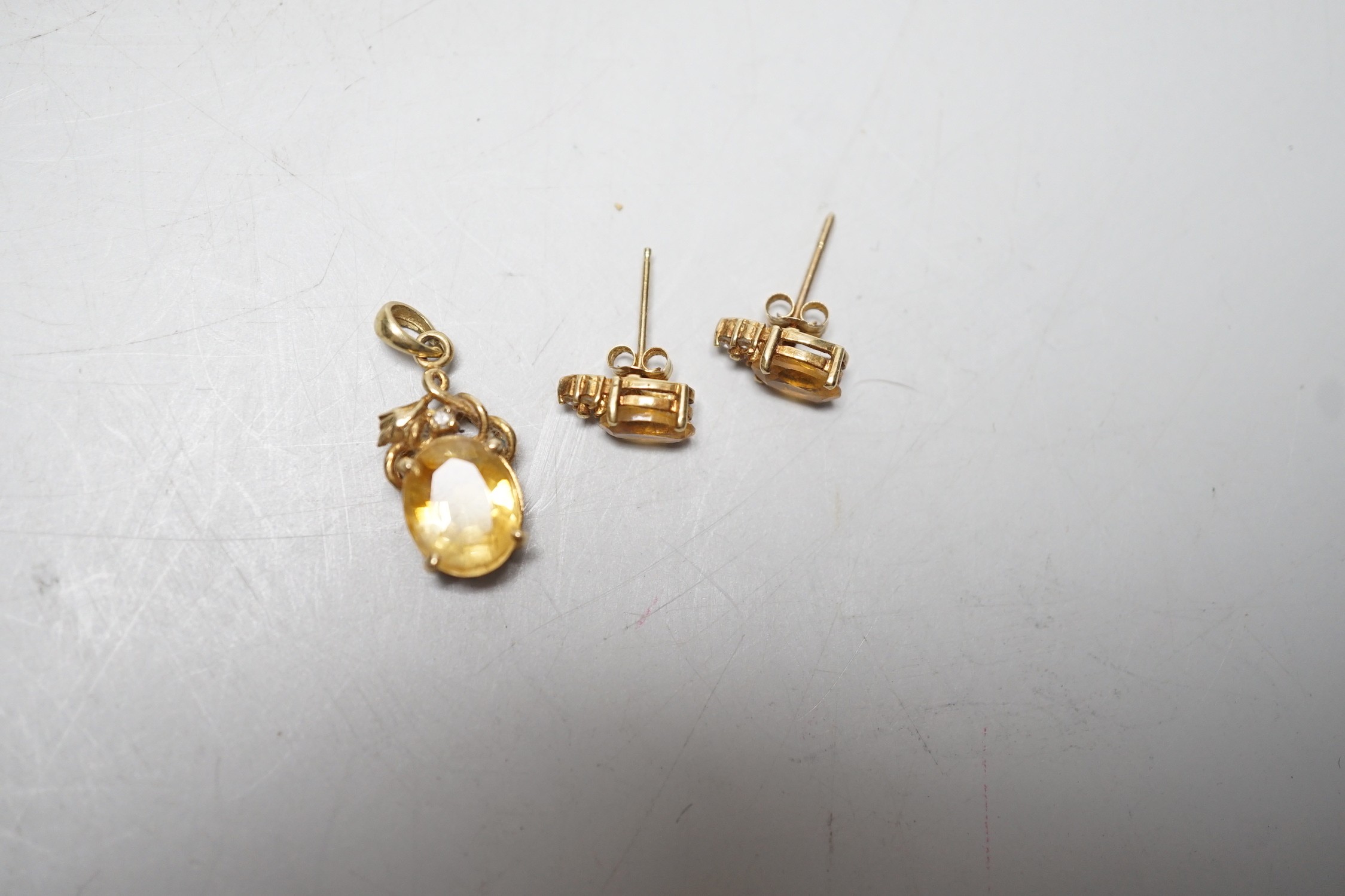 A modern 14k, citrine and diamond chip set pendant, 15mm and a pair of matching ear studs, gross weight 3.1 grams.